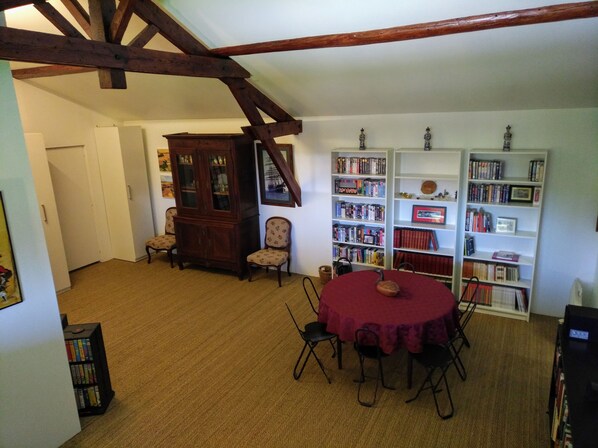 A room with a round table, chairs, a wooden cabinet, and bookshelves filled with books.