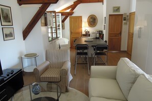 A modern living room with a sofa, armchairs, a coffee table, and a dining area with a table and chairs.