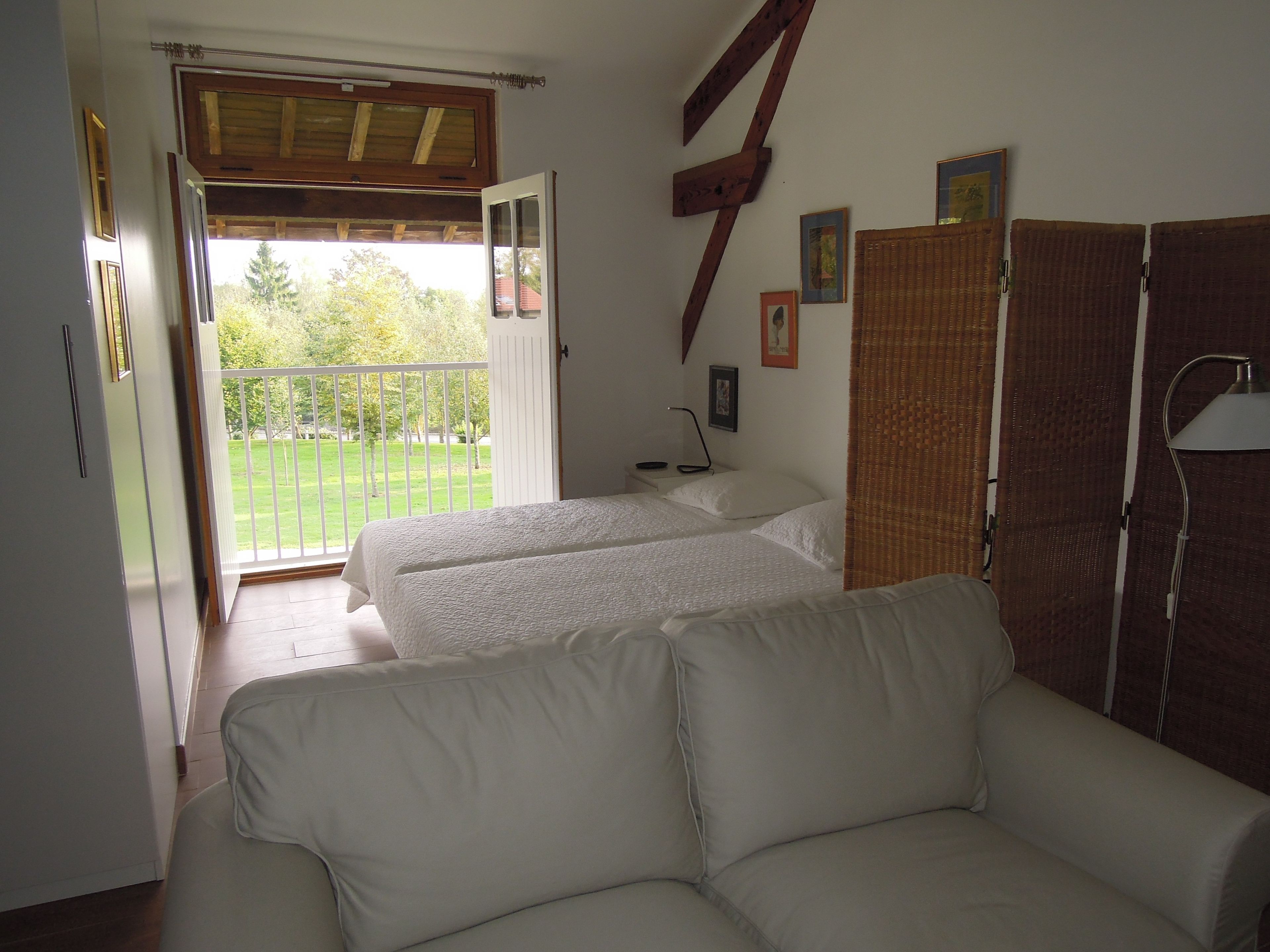 Un dormitorio con cama, sofá, armario y balcón con vistas a zonas verdes.