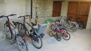 Bicicletas estacionadas en el interior, con piso de concreto y paredes de piedra.