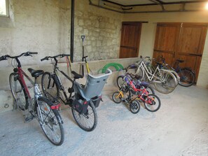 Bicycles parked indoors with a concrete floor and stone walls.