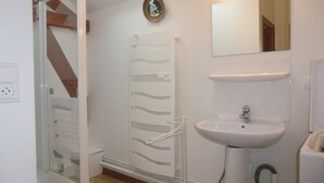 Une salle de bain équipée d’une douche, d’un lavabo, d’un miroir et d’un porte-serviettes.