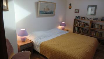 Une chambre à coucher avec un lit, des lampes de chevet, une bibliothèque et un tableau au mur.