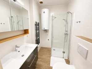 A modern bathroom with a glass shower enclosure, a white sink, and a toilet. - Smarthotel Schmid (Sitzenberg)