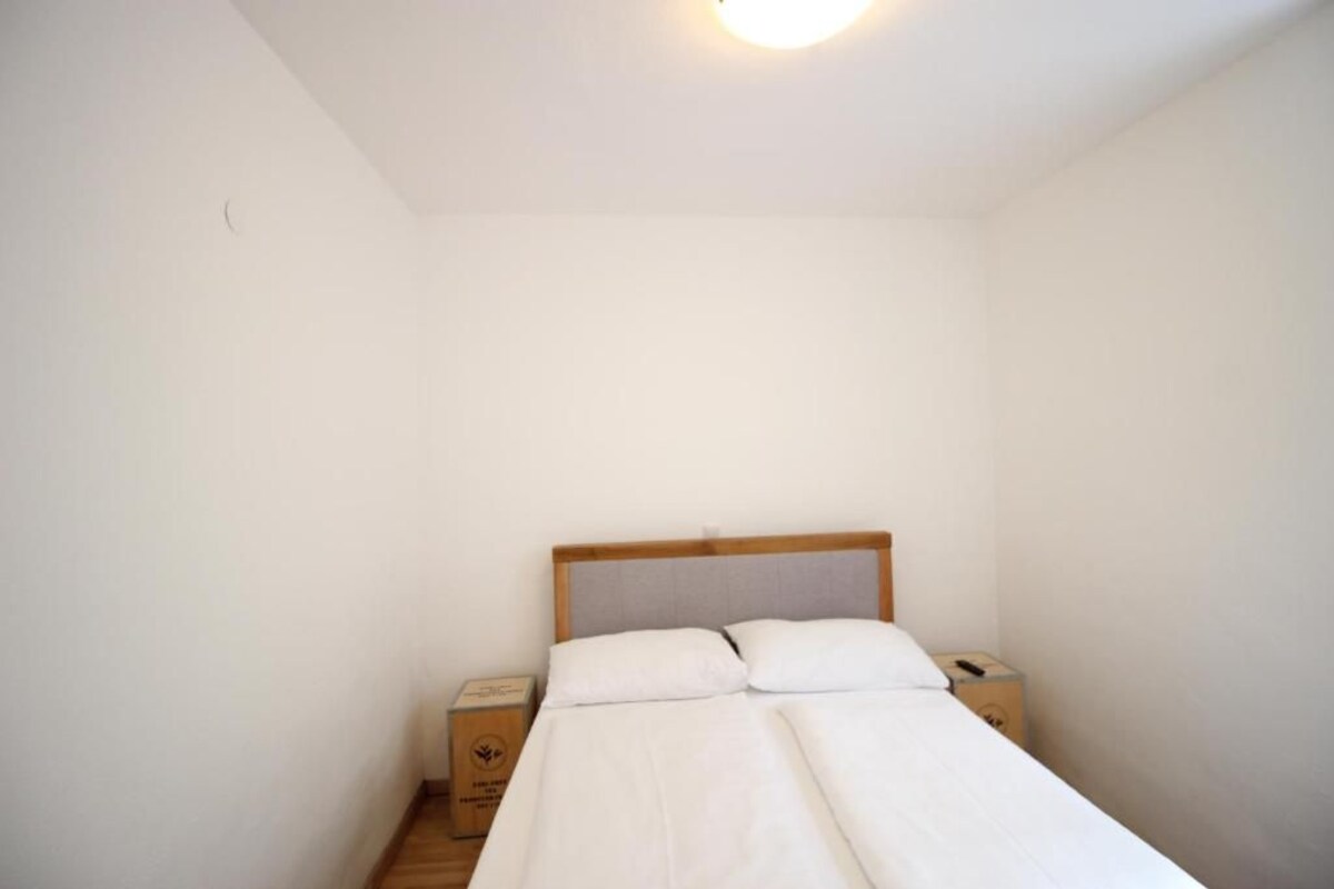 A small, single-bed room with a wooden headboard, two bedside tables, and a nightstand.