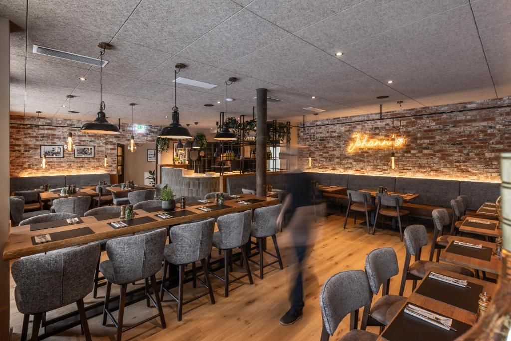 A restaurant with a brick wall, hanging pendant lights, and a neon sign.