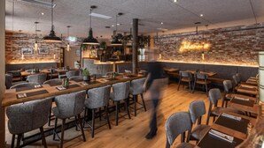 Ein Restaurant mit Backsteinwand, hängenden Pendelleuchten und einem Neonzeichen.