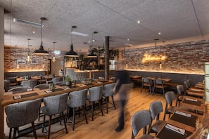 Un restaurant avec un mur en briques, des suspensions lumineuses et un néon.