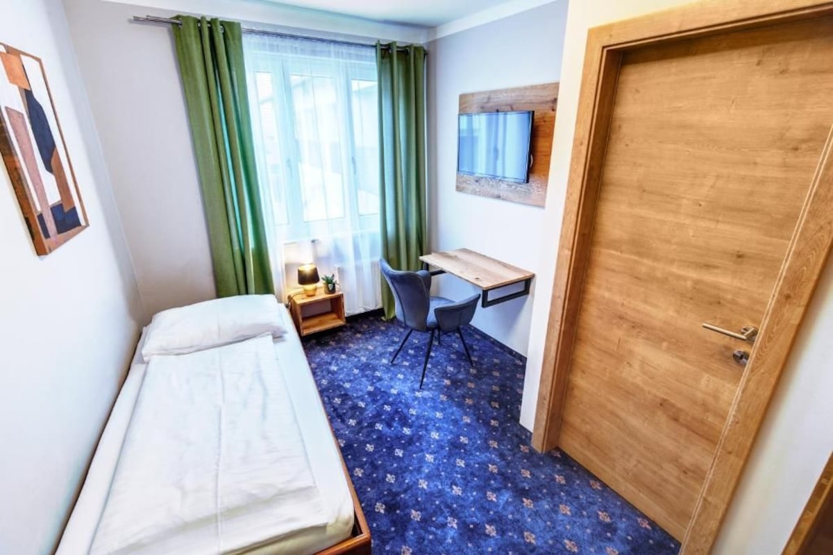 Une chambre d’hôtel avec un lit, un bureau, une chaise et une porte en bois.