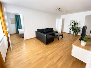 Een moderne woonkamer met een hoekbank, een salontafel en een televisie op een houten dressoir.
