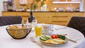 Ein Frühstückstisch mit Rührei, Gemüse und einem Glas Orangensaft.