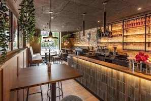 A modern bar area with seating, a counter, and a variety of bottles on shelves. - Smarthotel Schmid (Sitzenberg)
