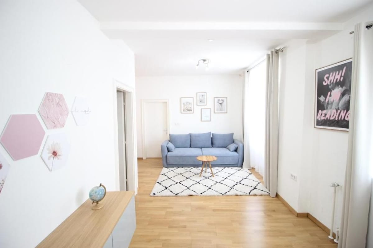 Un couloir avec un canapé bleu, un tapis à motifs et un globe terrestre posé sur une table en bois.