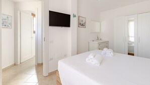 Habitación de hotel con cama, televisión montada en la pared, escritorio pequeño y armario.