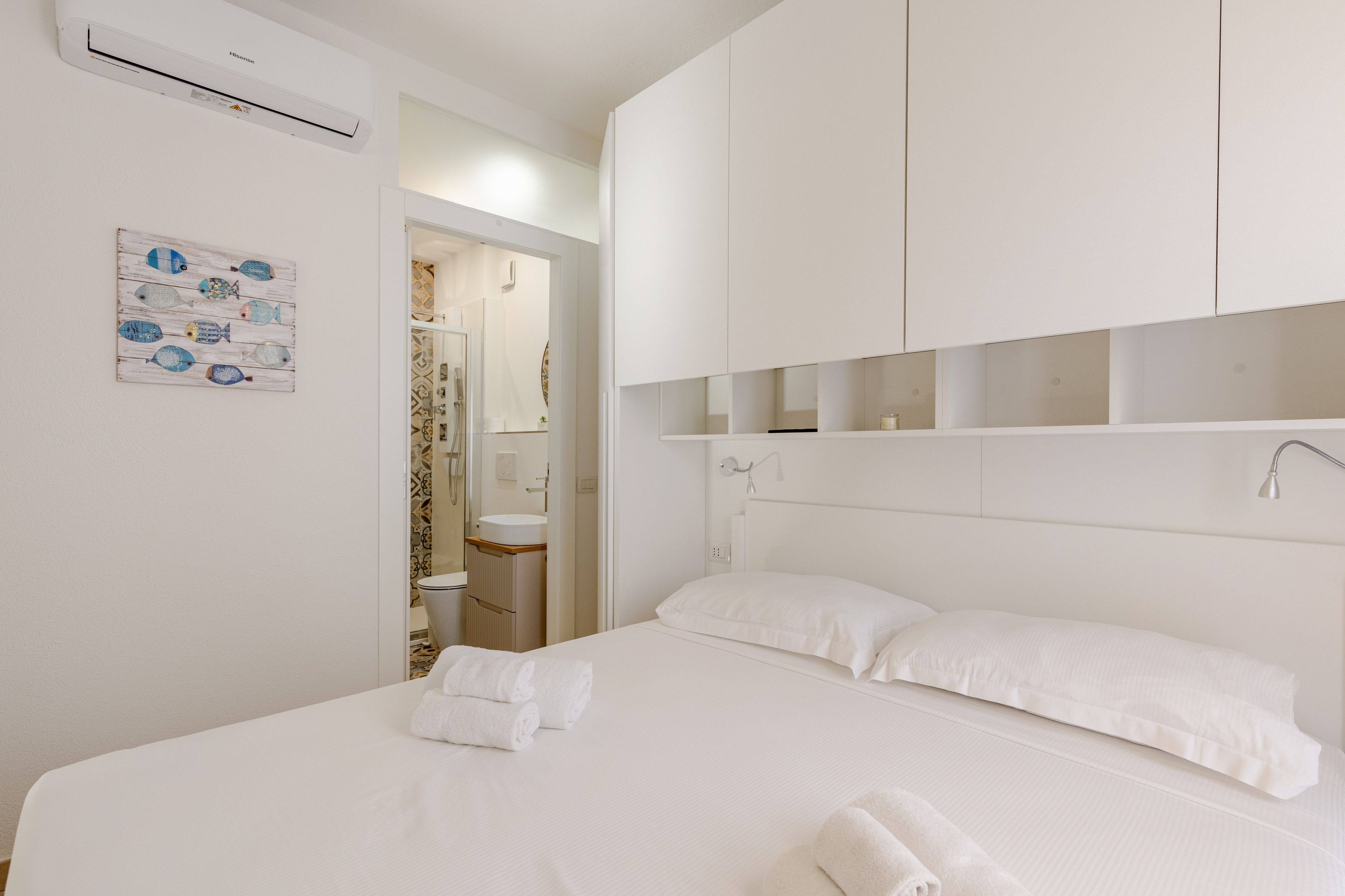 A hotel room with a bed, a bathroom, and a mounted air conditioner.