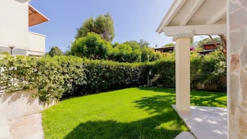 A well-maintained garden with a lawn, a hedge, and a building with a white exterior.