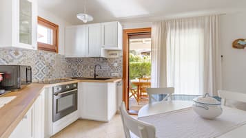 Eine kompakte Küche mit Backofen, Spüle und Essbereich mit Tisch und Stühlen.