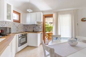 A compact kitchen with a built-in oven, a sink, and a dining area with a table and chairs.