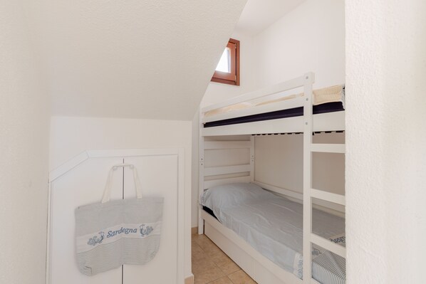 Habitación con literas, una ventana pequeña y una puerta.