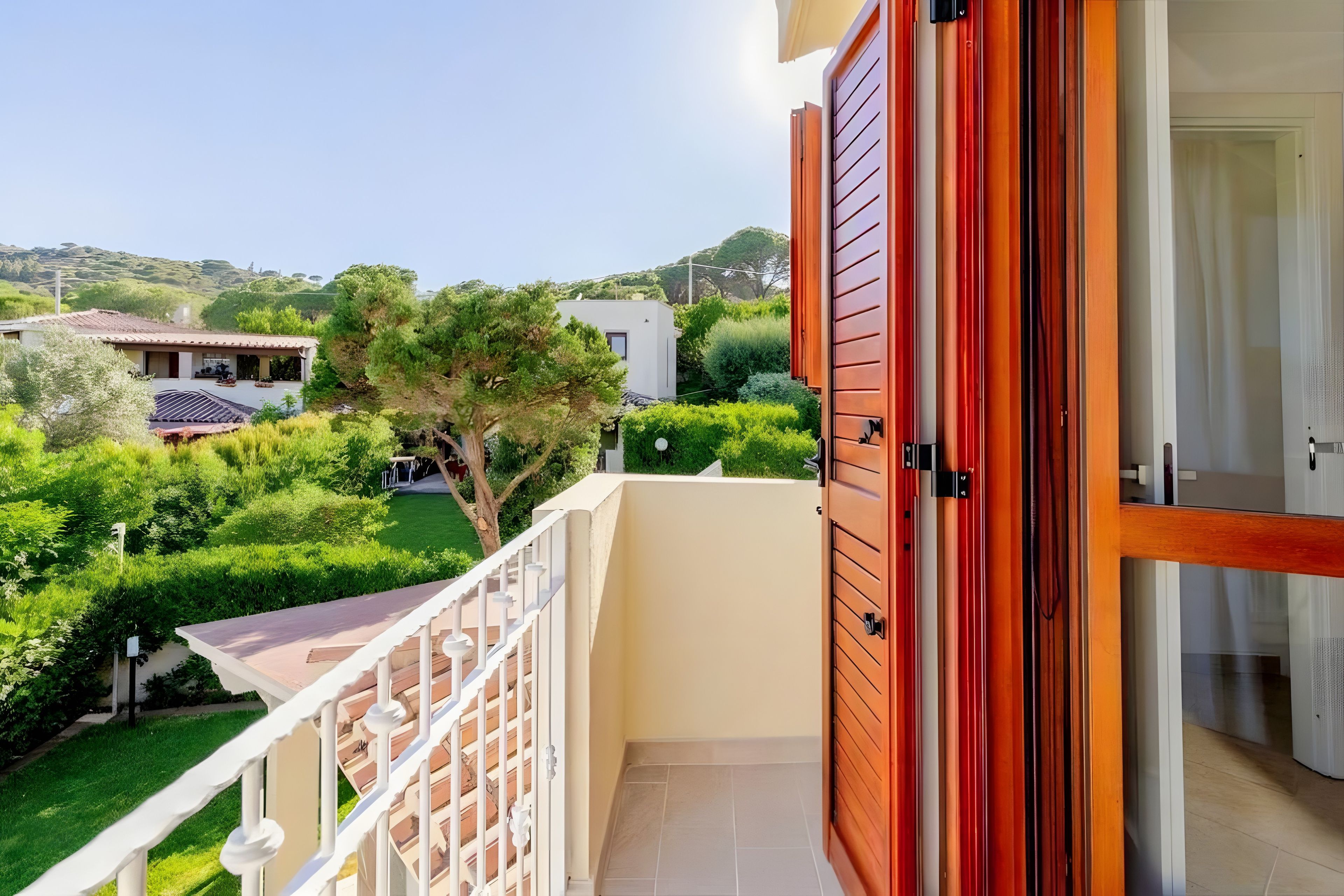 Ein Balkon mit Blick auf eine grüne Landschaft und ein Gebäude im Hintergrund.