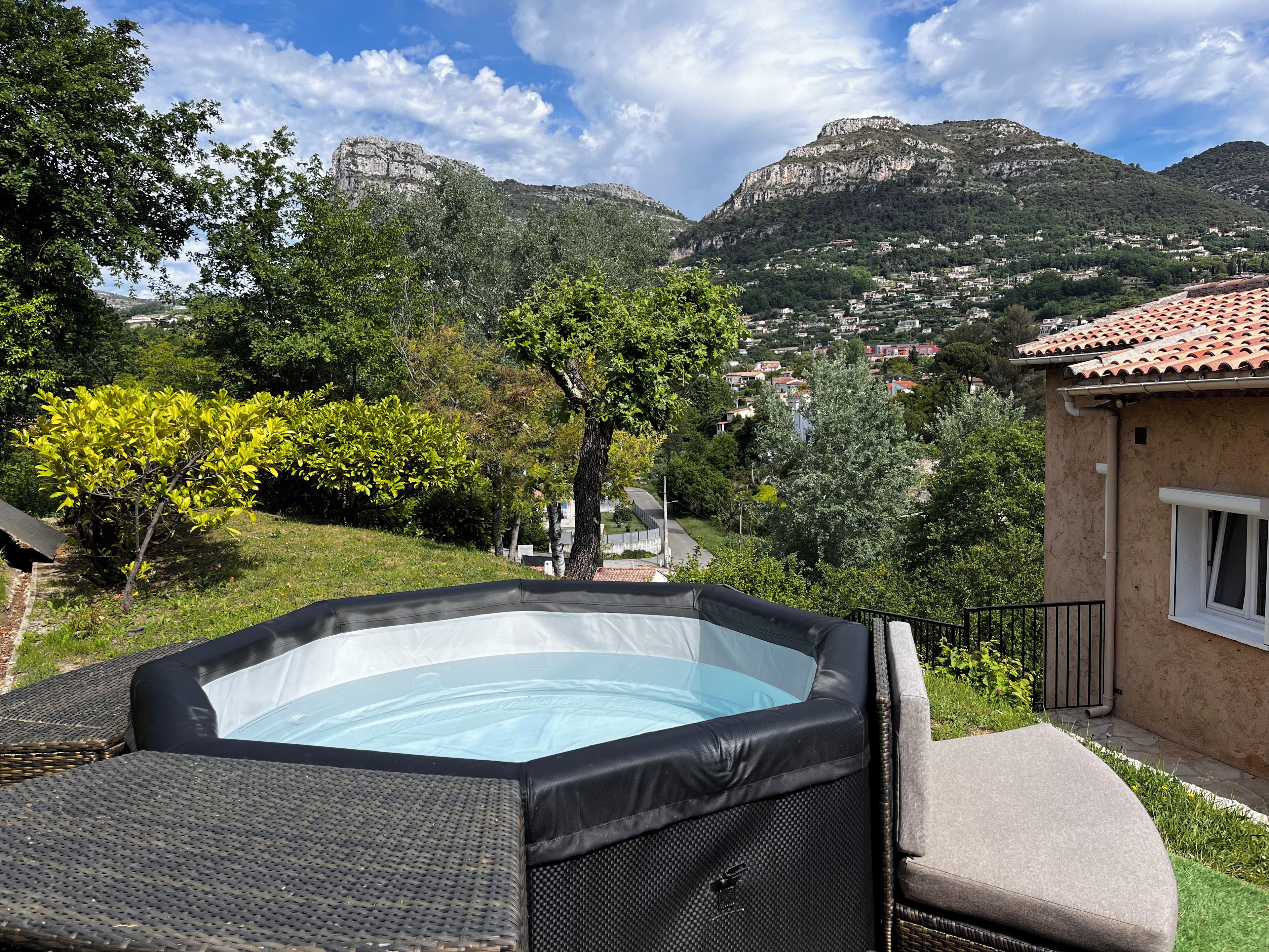 Un bain à remous avec vue sur un paysage montagneux et une maison avec un toit en tuiles.