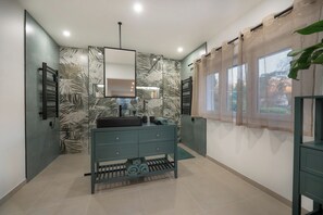 A bathroom with a modern design, featuring a large mirror, a sink, and a towel rack.