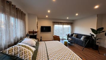 Ein Hotelzimmer mit einem großen Bett, einer Couch, einem Fernseher und einer Pflanze.