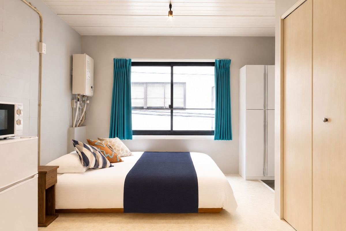 Ein Schlafzimmer mit einem Bett, einem Fernseher, einem Kleiderschrank und einem Fenster mit Vorhängen.