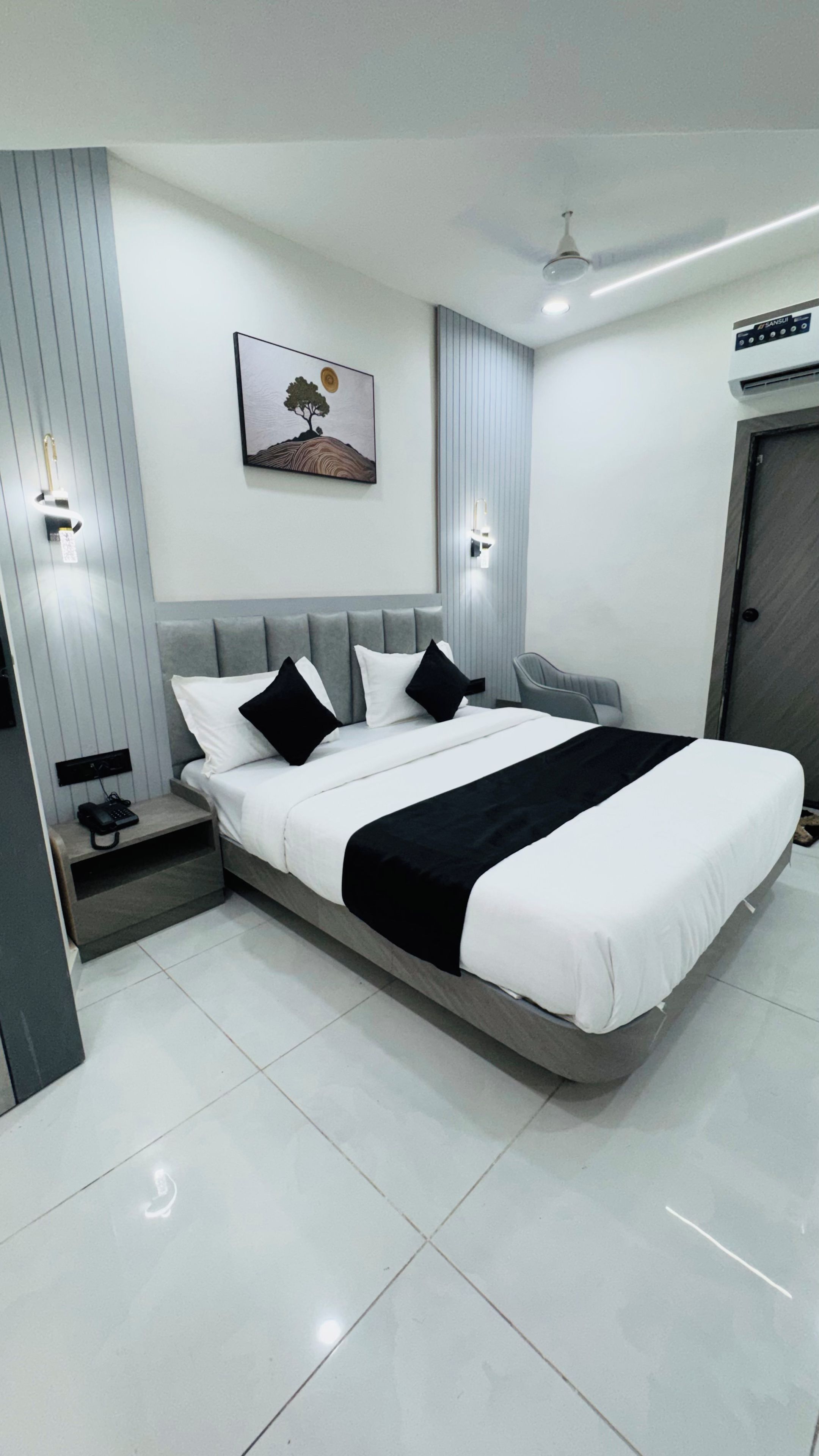 A modern bedroom with a bed, bedside table, and a wall-mounted artwork.