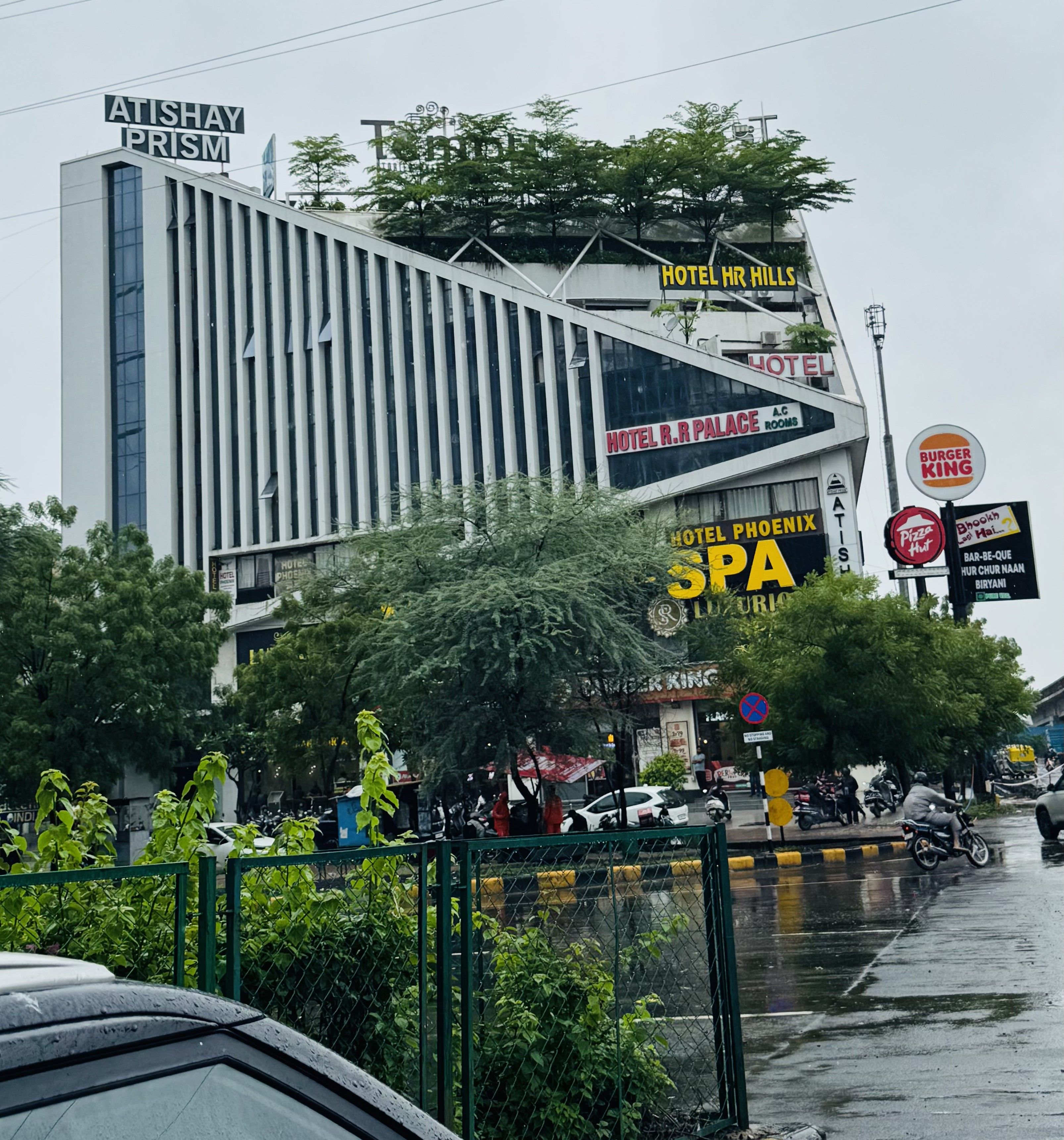 Et moderne hotel med flere skilte, der angiver forskellige faciliteter, herunder spa, restaurant og parkeringsmuligheder.