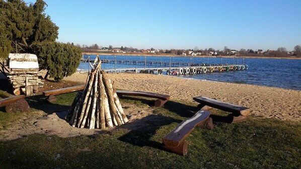 Area picnic sul lago con panchine e un focolare.
