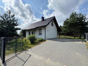 Et etplanshus med tegltag, en belagt indkørsel og en metalport.