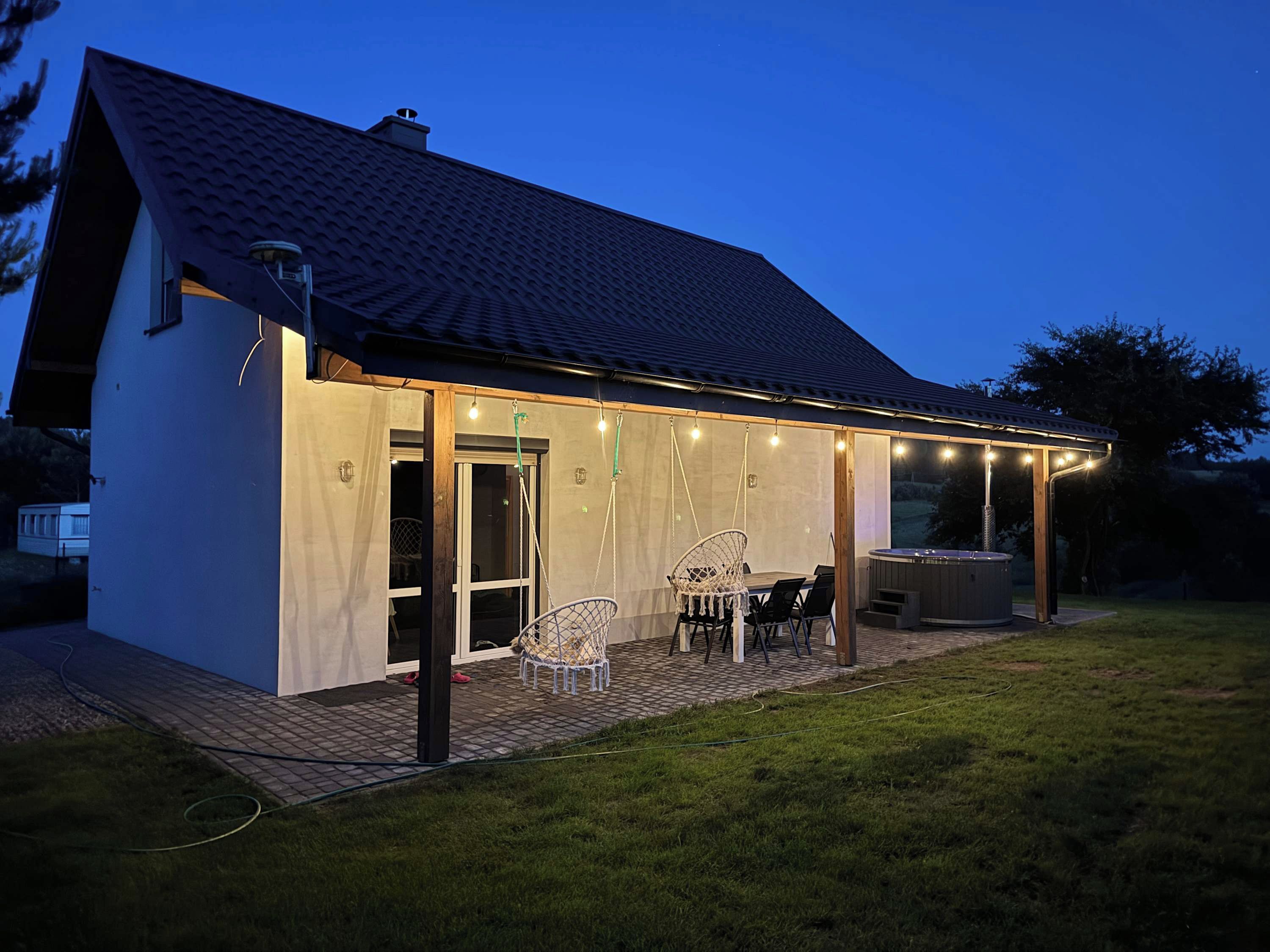 A house with a covered patio, outdoor seating, and a hot tub.