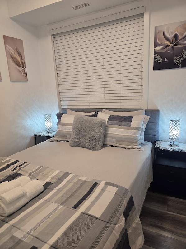 Quarto com cama, mesas de cabeceira e quadros nas paredes.