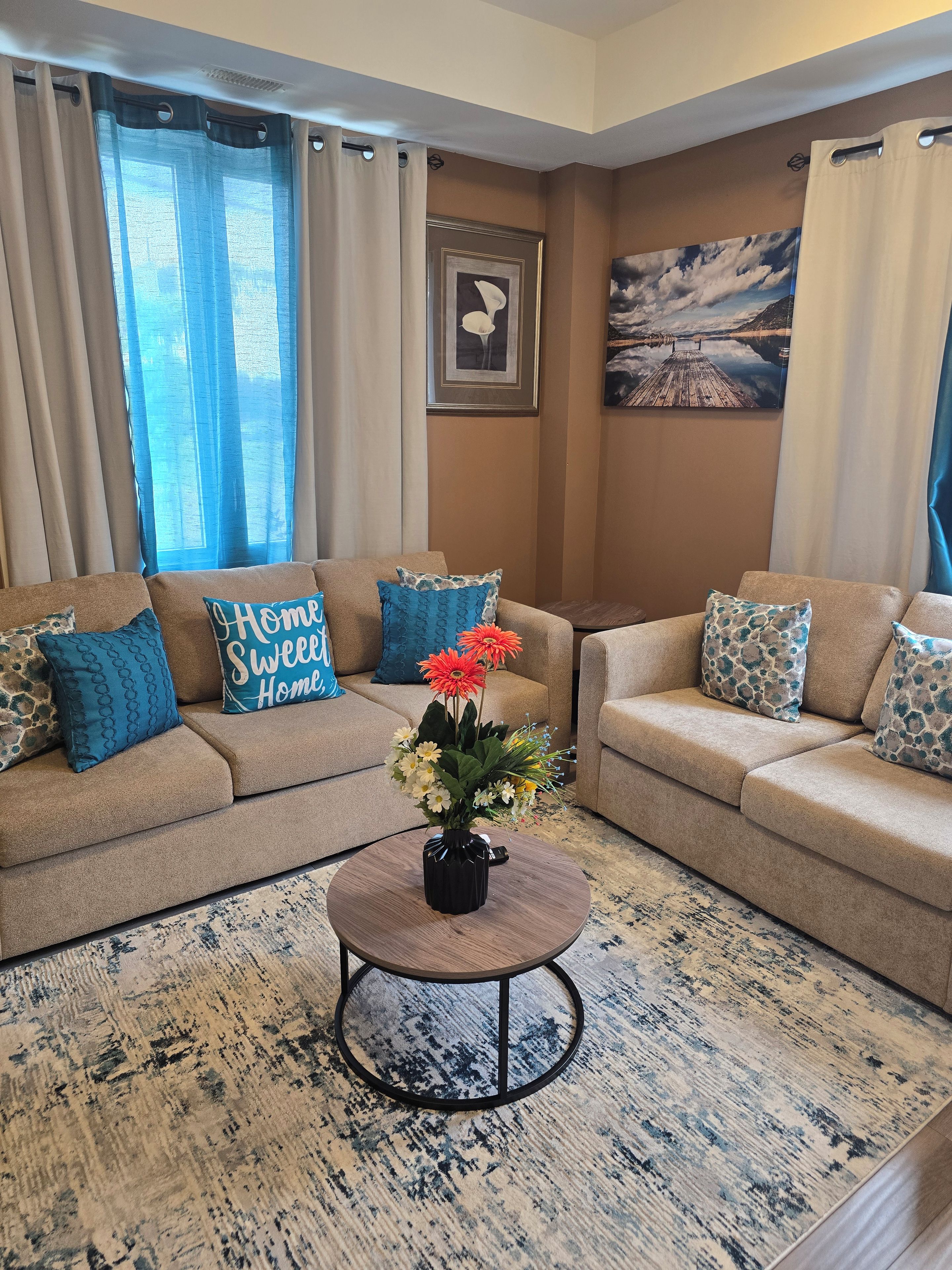 Un salon avec deux canapés beiges, une table basse ronde et un tapis à motifs.