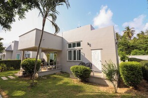 A modern two-story house with a covered patio, a small garden, and a view of the sky.