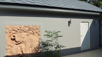 Een gebouw met een pannendak, een reliëf van een olifant, een deur en een klein plantje.