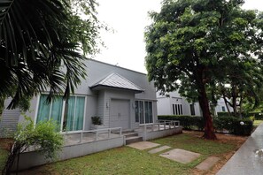 Una casa residencial con porche delantero, garaje y un gran árbol en el jardín.