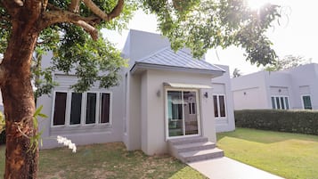 A modern two-story house with a white exterior, a covered porch, and a small front yard.