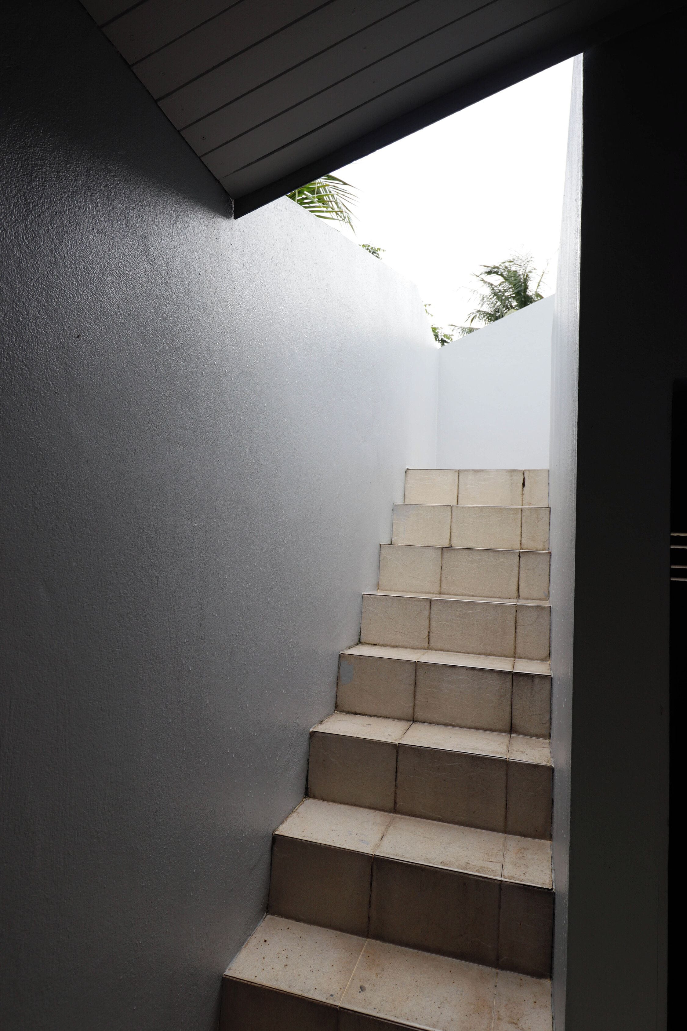 A staircase with beige steps leading upwards, surrounded by walls with a textured finish.