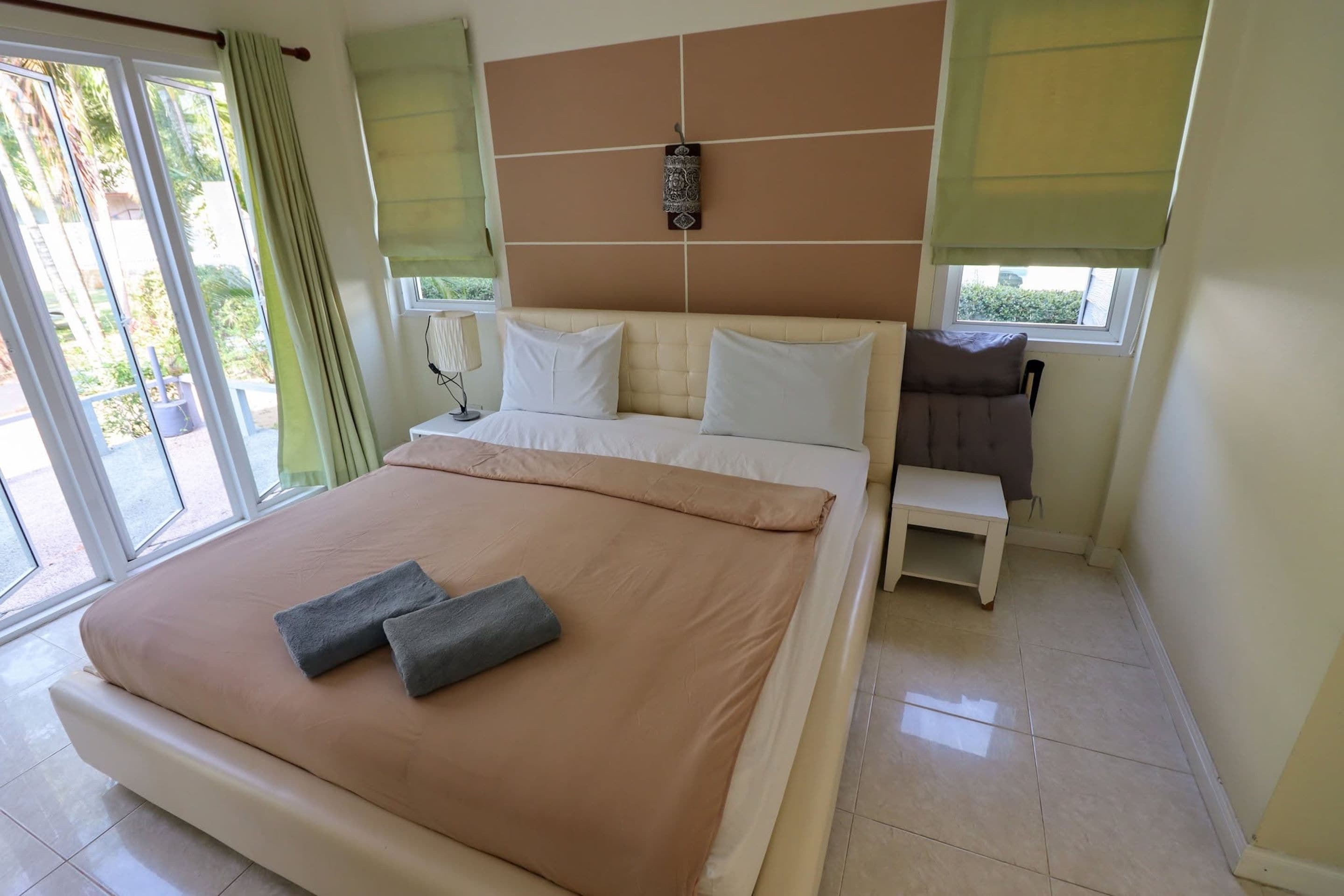 A hotel room with a bed, a bedside table, a window with a view, and a curtain.