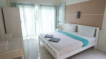 Un dormitorio con cama, mesita de noche, armario y ventana con cortinas.