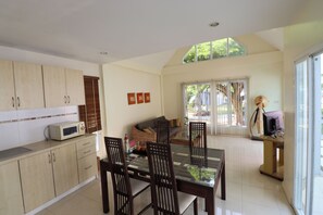A modern kitchen with a dining table and chairs, a microwave, and a sofa in the living area.