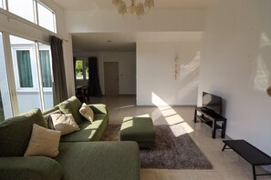 A living room with a sofa set, a TV, and a rug. - Seamount Ban Krut (Thong Chai)