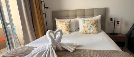 A hotel room with a bed, a bedside table, a lamp, and an air conditioning unit.