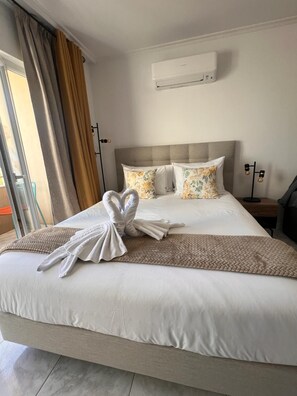 Ein Hotelzimmer mit einem Bett, einem Nachttisch, einer Lampe und einer Klimaanlage.