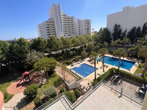 Ein Wohngebiet mit Schwimmbad, Palmen und einem großen Gebäude im Hintergrund.