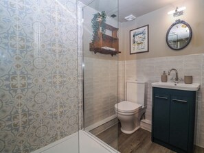 Un bany amb rajoles decorades, un vàter, un lavabo amb un armari i un mirall.