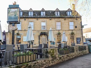 Ein traditionelles Steinhaus mit einem Schild, das 'Old Manse Hotel' und 'Greene King' zeigt.