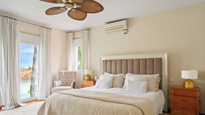 A hotel bedroom with a large bed, a chair, a nightstand, and a ceiling fan. - Luxury villa in Marbella (Marbella)